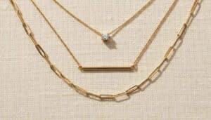 A layered arrangement of elegant chains showcases a dainty gold necklace that adds a subtle, refined touch to the minimalist backdrop.