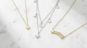 Types of star necklaces flat lay including dainty gold star pendant, layered silver star set, and shooting star necklace on white marble